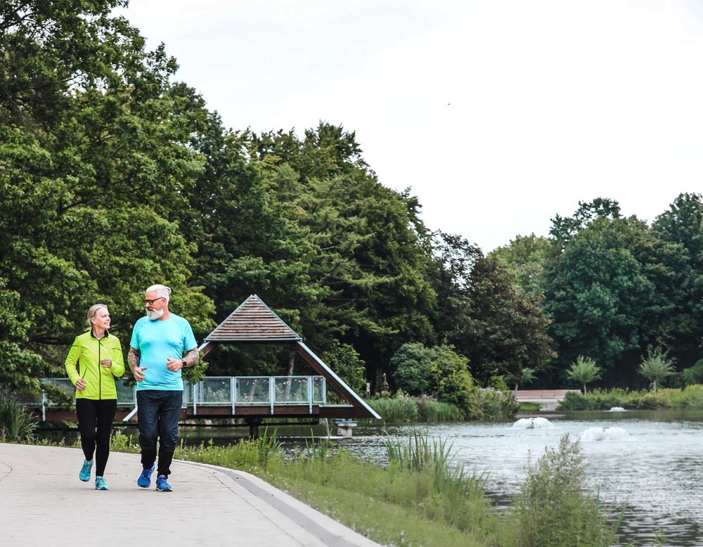 Zwei Jogger im Kurpark Bad Sassendorf. Sie joggen entlang des Sees.