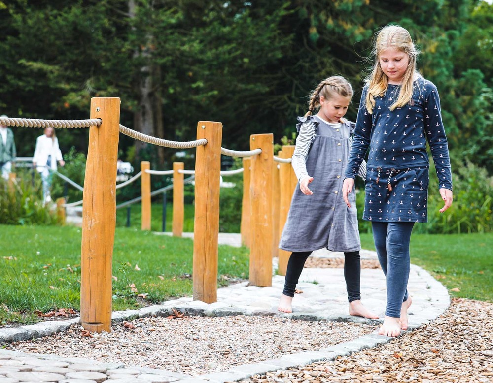 Zwei Kinder erkunden den Barfußpfad des Kurparks Bad Sassendorf.