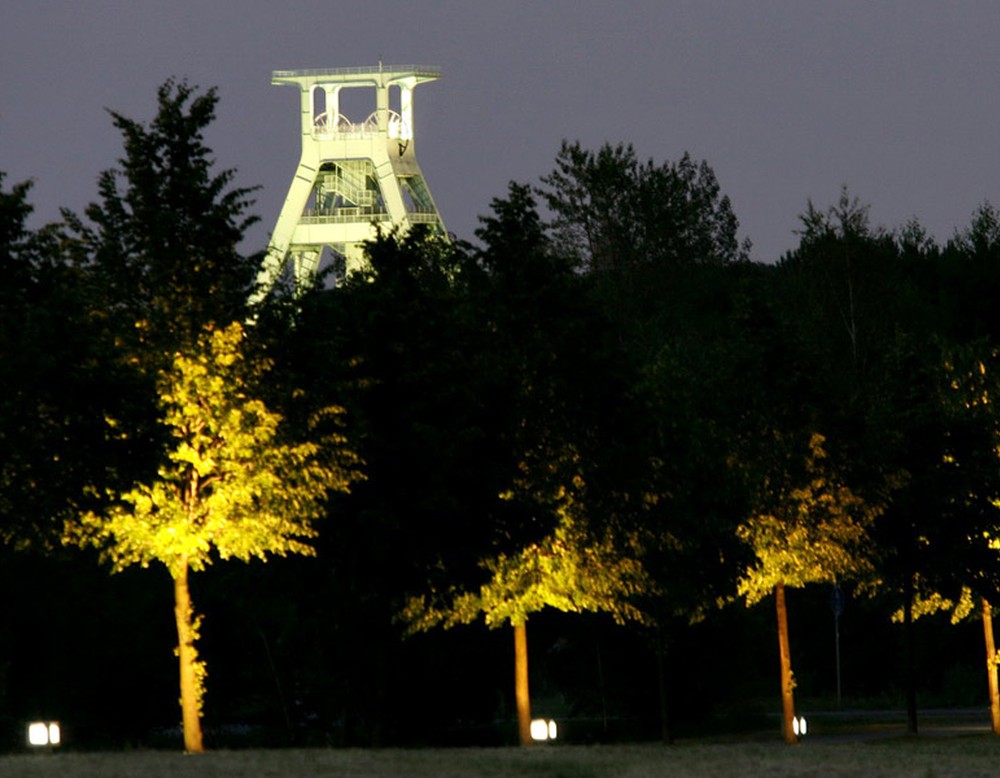 Beleuchteter Bäume sowie der beleuchtete Förderturm des Deutschen Bergbaumuseums in Bochum.